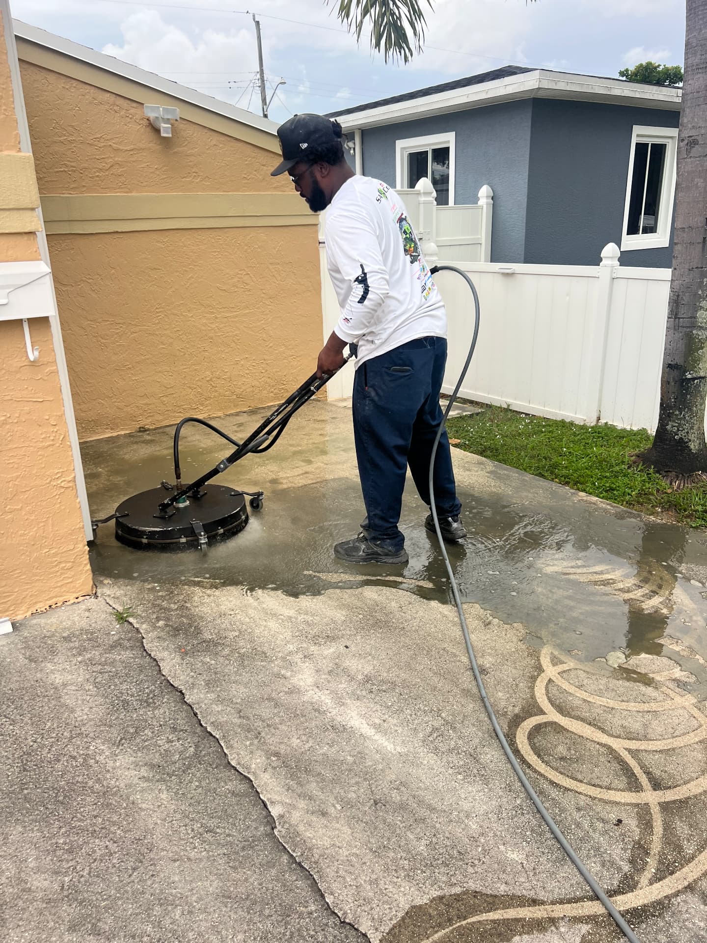Driveway being surface cleaned, bright concrete emerging from grime